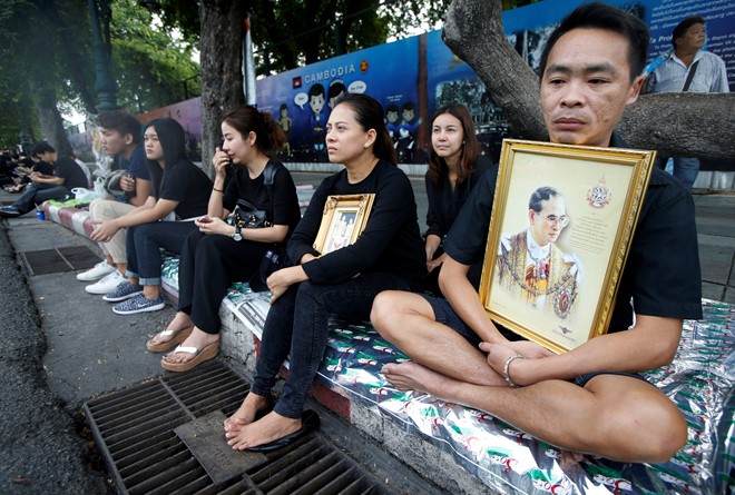 Người dân mặc áo đen, ngồi hai bên đường chờ đoàn xe chở linh cữu Quốc vương Bhumibol đi qua. Ảnh: Reuters.